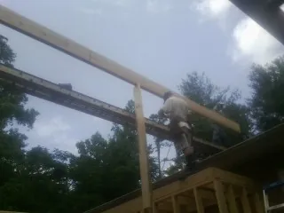 Carpenter setting a ridge beam over a new addition frame — Ice Dam Removal by Roofing Brothers in Bradenville