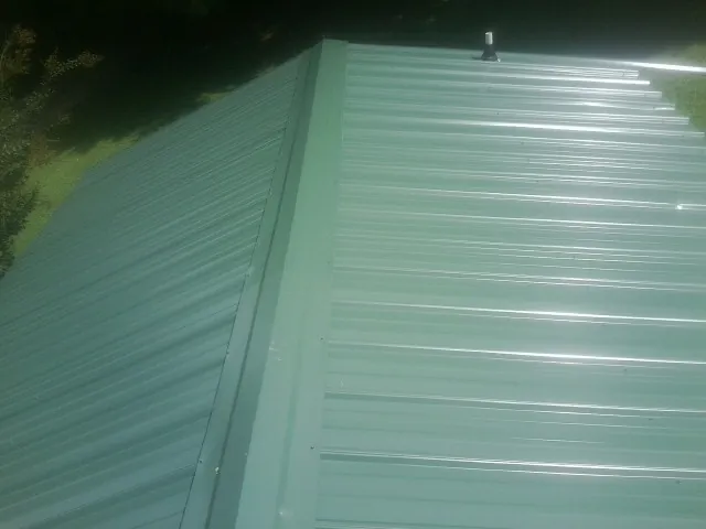 New green metal panels meeting at the ridge of a roof — Flat Roof Repair work by our crew in Bradenville