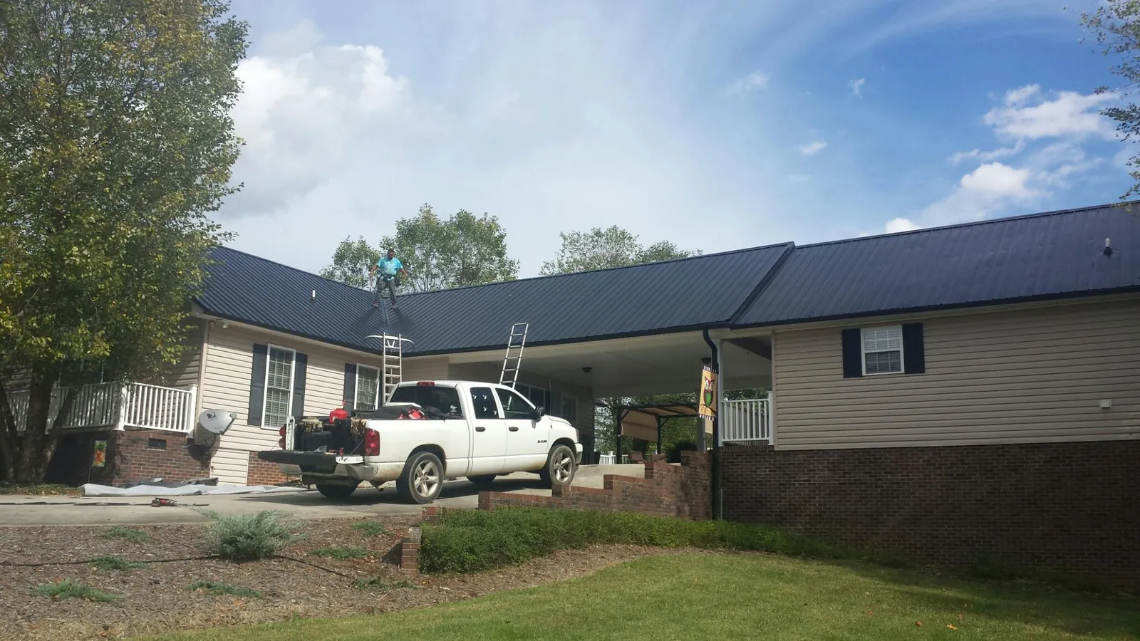 Black metal roof over a home and attached breezeway with ladders set in Bradenville