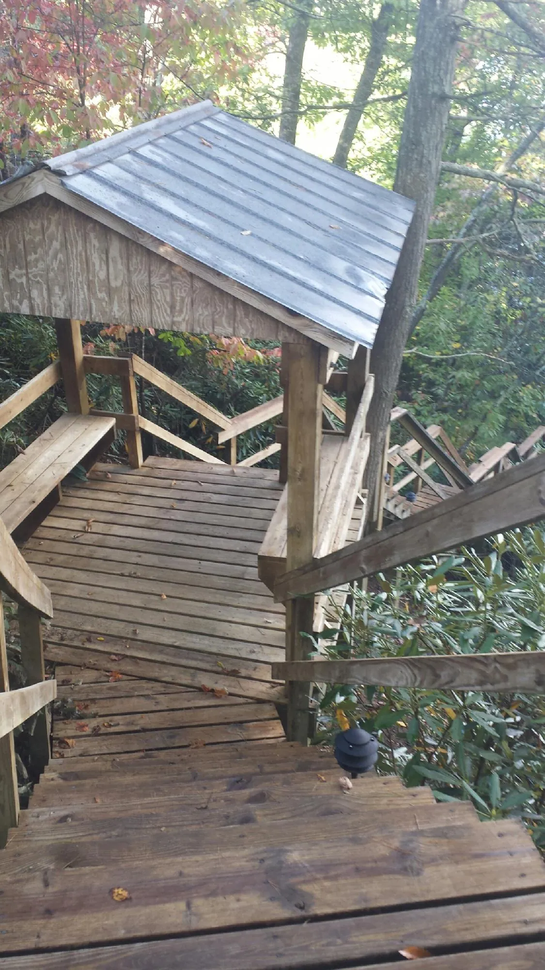 Metal roofed shelter over wooden steps on a wooded walkway — Skylight Repair & Installation work by our crew in Bradenville