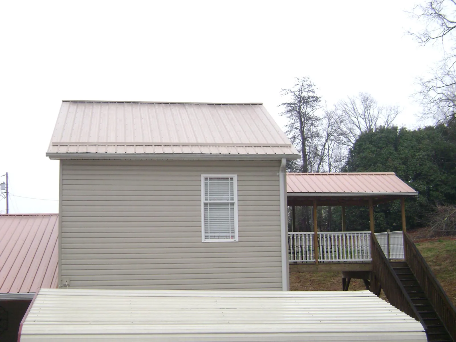 Tan metal roofs on a two story addition and attached porch, from a Roof Replacement job in Bradenville