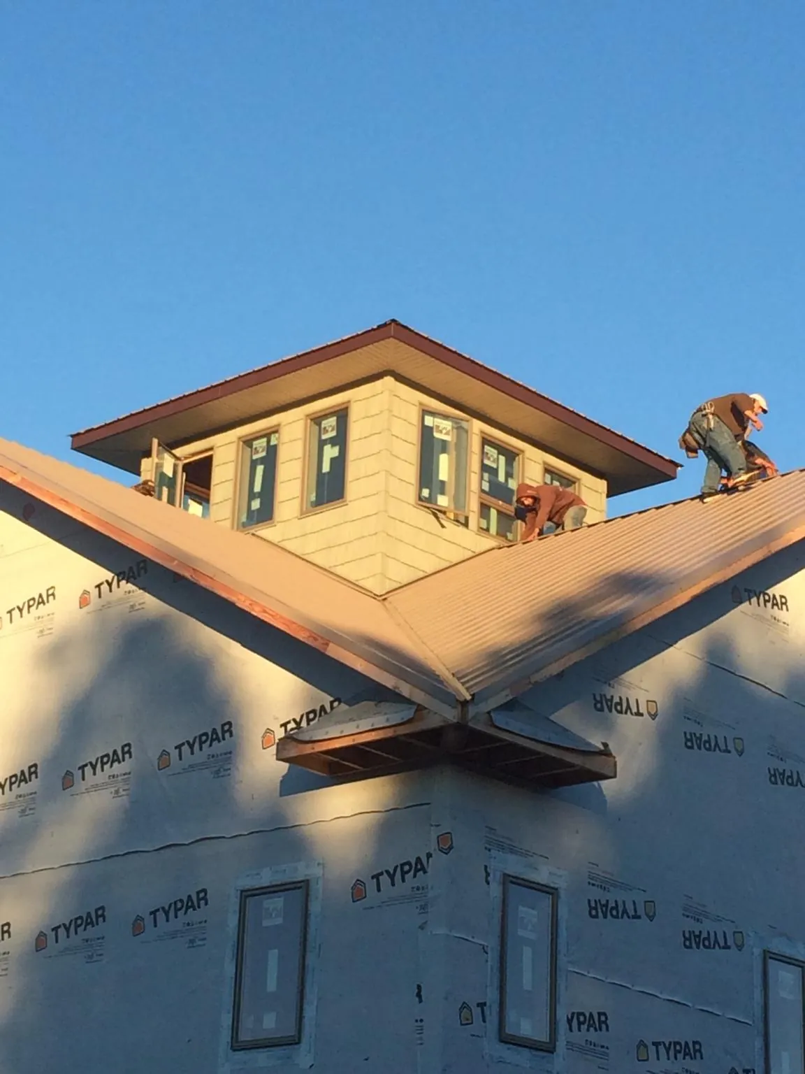 Roofers working around a rooftop cupola on a new metal roof at sunset — Roof Waterproofing in Bradenville by Roofing Brothers